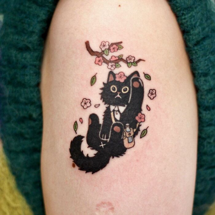 Tattoo of a black cat with flowers and branches, showcasing adorable animal-themed design.
