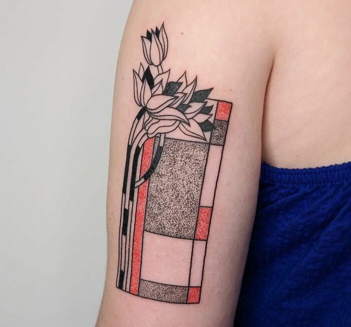 Geometric tattoo with abstract shapes and floral design on arm, featuring red and black colors.