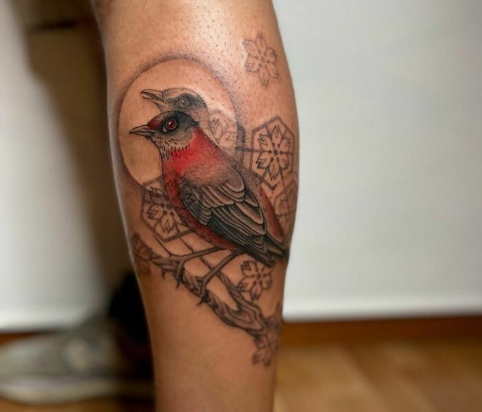 Geometric tattoo featuring a bird with floral patterns on a person's leg.