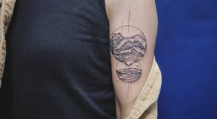 Geometric tattoo on upper arm with mountain and ocean design inside a circle.