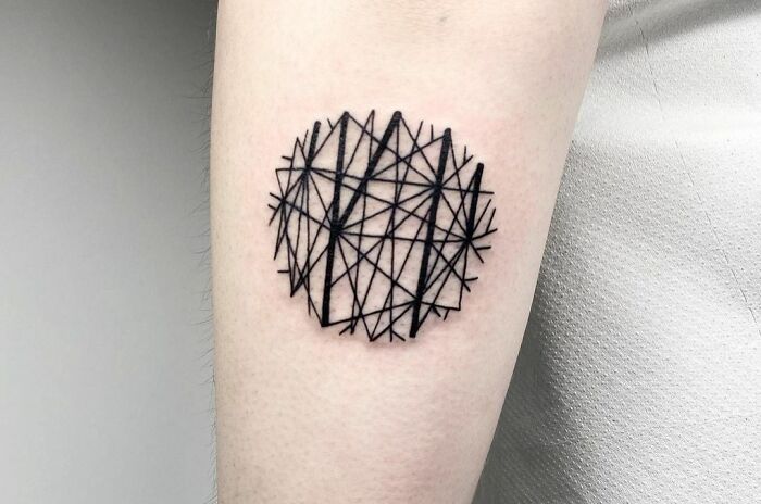 Geometric tattoo design with intersecting black lines on forearm.