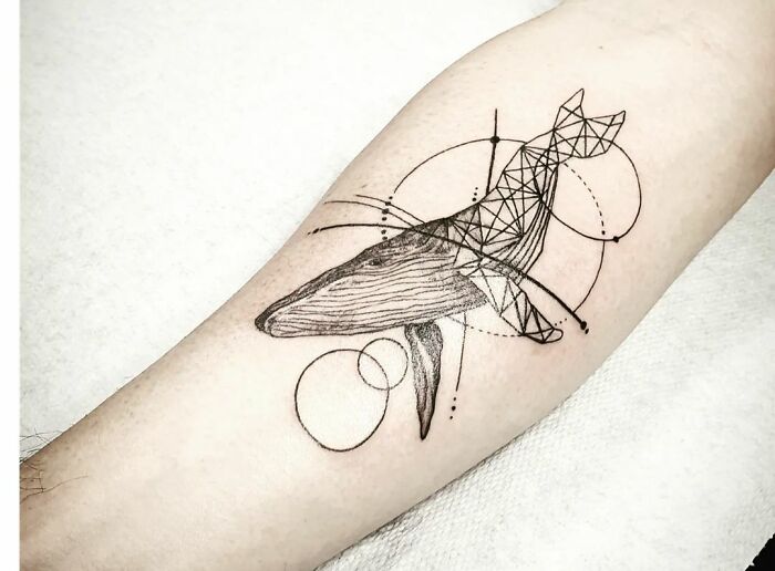 Geometric tattoo featuring a whale with intricate lines and circles on a forearm.