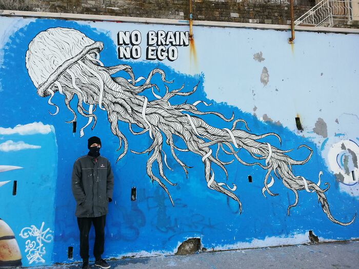 Creative graffiti art of a jellyfish with tentacles on a blue wall, turning a blank space into a work of admiration.