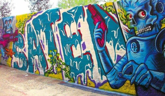 Colorful creative graffiti art on a large outdoor wall featuring vibrant characters and bold text in urban style.