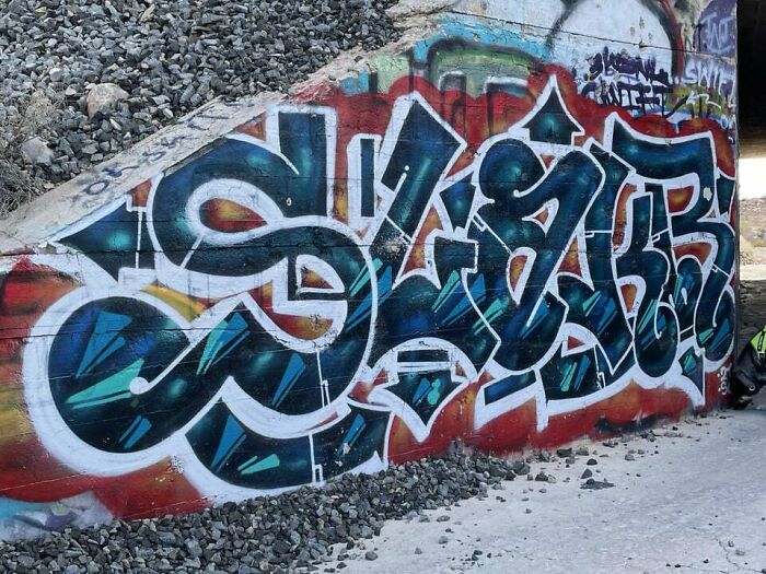 Graffiti art with bold colors and dynamic shapes transforming a blank concrete wall into a striking urban masterpiece.