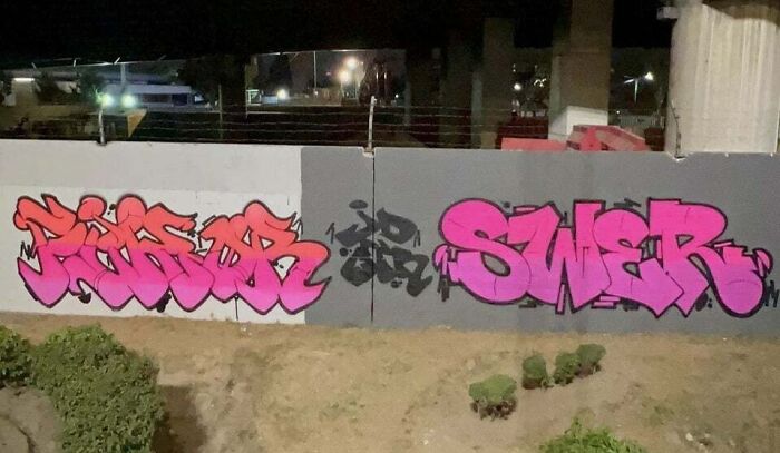 Colorful creative graffiti art in pink and red transforming a blank urban wall into an object of admiration at night.