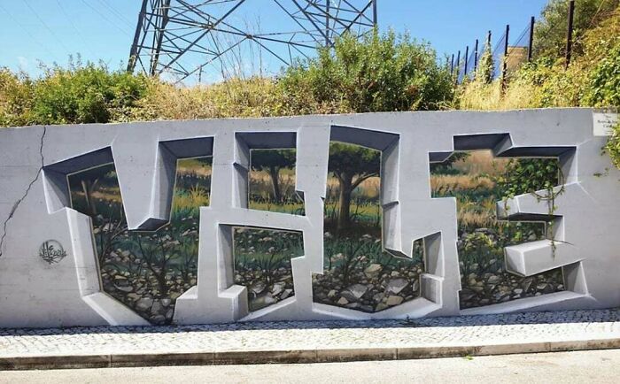 3D graffiti art on a concrete wall creating a realistic landscape scene within bold letters.