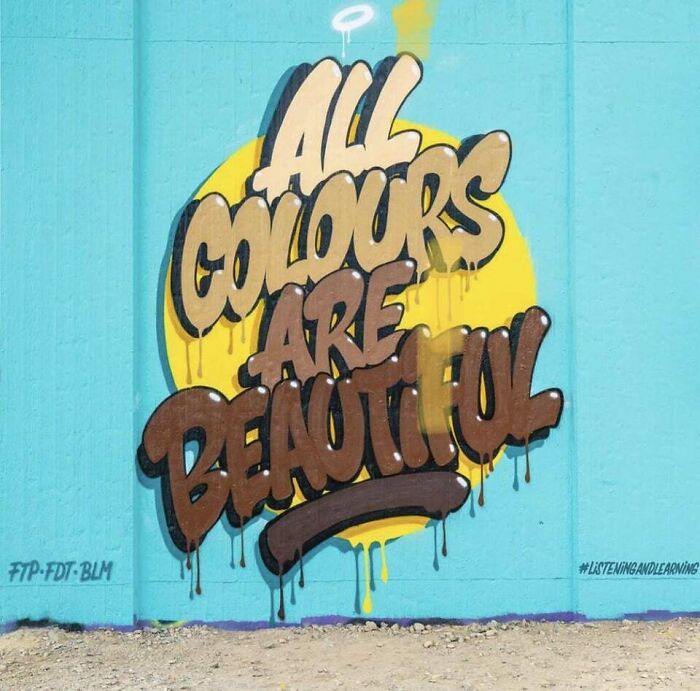 Graffiti art on a blue wall with the phrase all colours are beautiful in bold dripping letters.