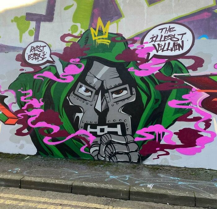 Graffiti art of a masked figure in a green hood with pink and purple smoke on a concrete wall, vibrant street art.