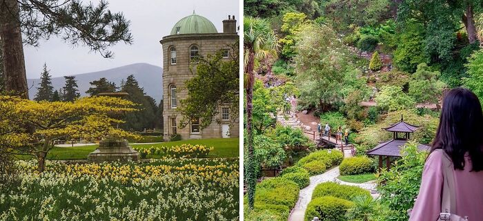 A lush famous garden with blooming flowers and trees beside a historic building and a winding path with visitors in greenery.