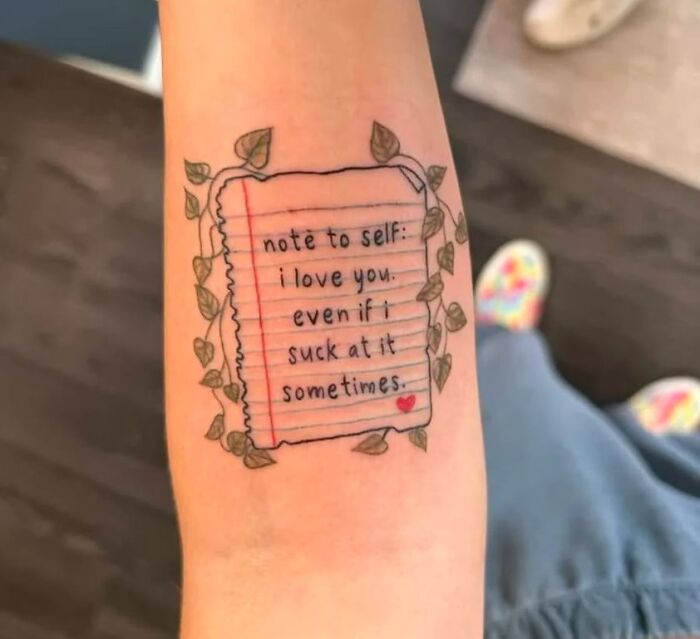 Tattoo of a handwritten note surrounded by leaves, reading “note to self: I love you, even if I suck at it sometimes.”