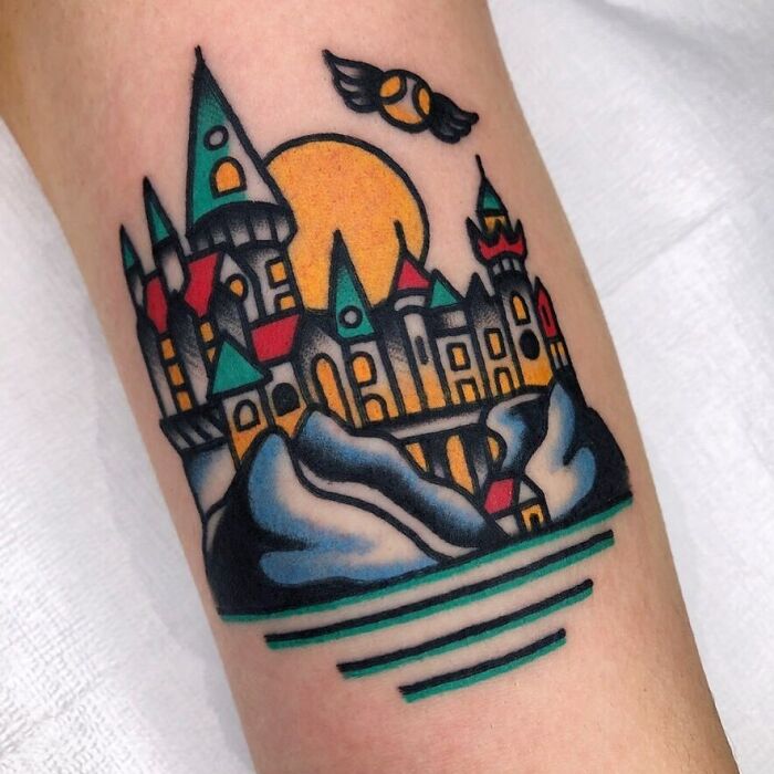 Colorful Harry Potter tattoo featuring Hogwarts castle and a golden snitch.