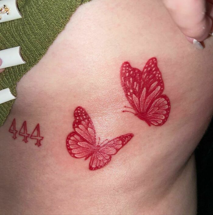Red ink tattoo design featuring two butterflies and the number 444 on skin.