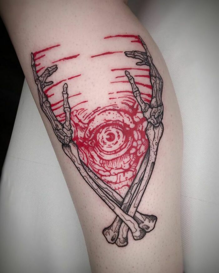 Red ink tattoo design with skeletal arms and swirling patterns on skin.