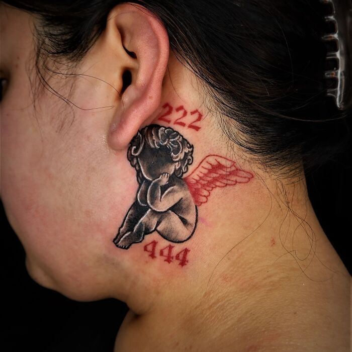 Red ink tattoo of an angel with wings and numbers 222, 444 on the neck.