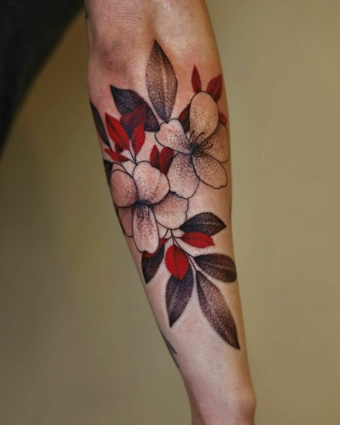 Red ink tattoo design featuring floral patterns on forearm.