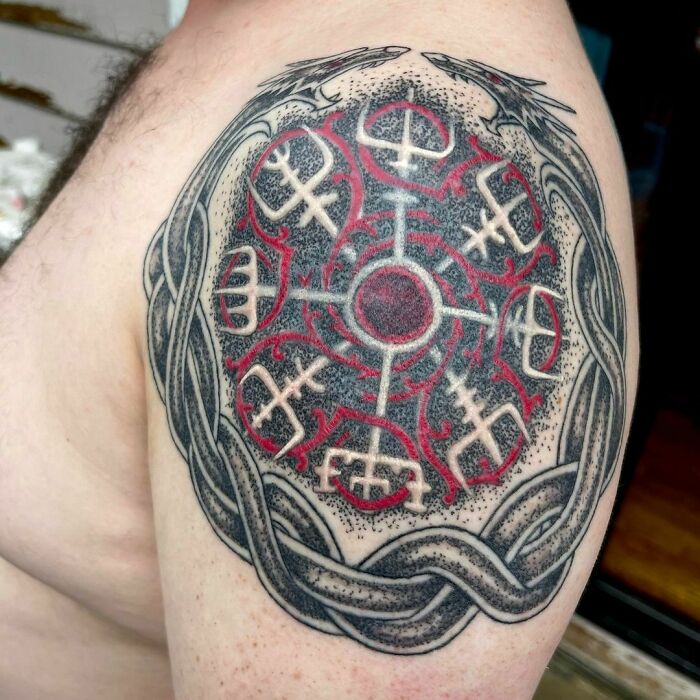 Red ink tattoo with intricate Viking-style patterns on upper arm.