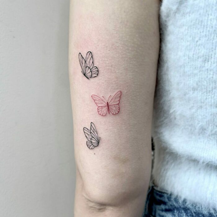 Red ink tattoo design of butterflies on a person's arm.