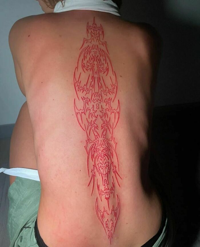Intricate red ink tattoo design on a person's back, showcasing unique style and artistry in red tattoo ideas.