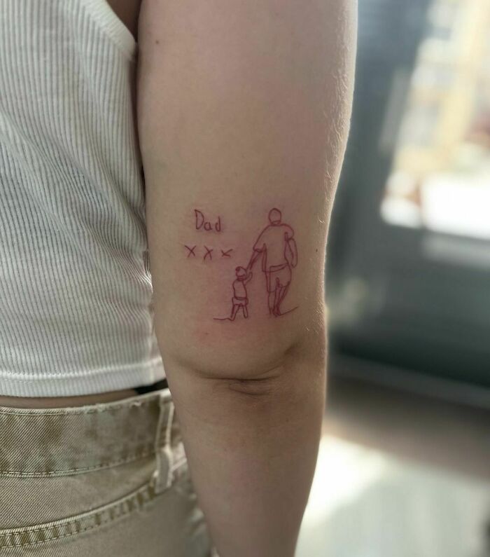 Red ink tattoo of a dad holding hands with a child, minimalistic design on an arm.