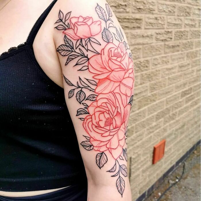 Red ink tattoo of roses on arm, showcasing intricate floral design.