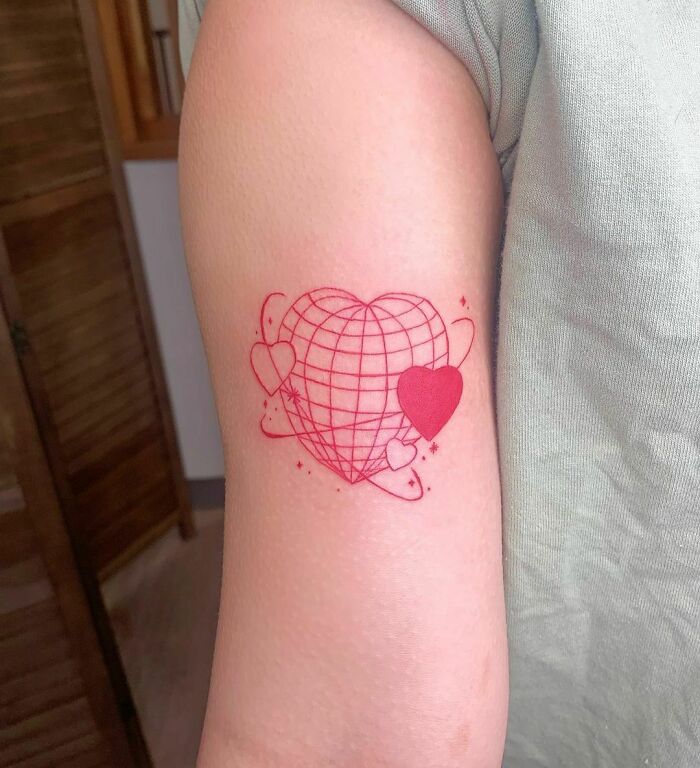 Red ink tattoo of a geometric heart design with smaller hearts on an arm.
