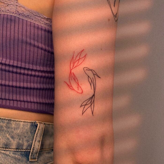 Minimalist red ink tattoo of koi fish on a person's arm.