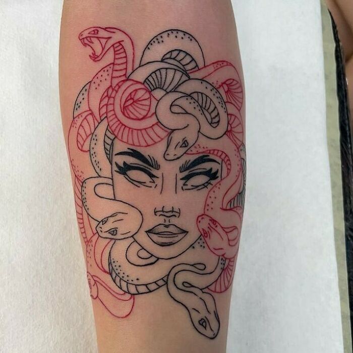 Red ink tattoo featuring Medusa with snakes, incorporating bold linework and intricate red design.