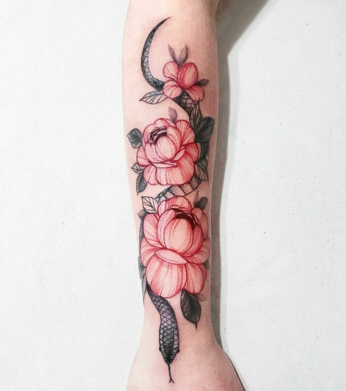 Red ink tattoo design featuring roses and a snake on an arm.
