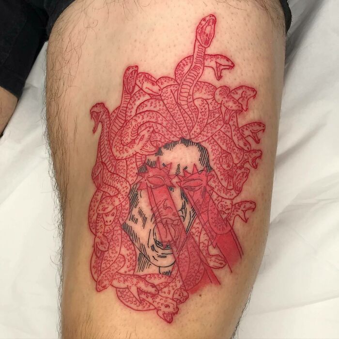 Red ink tattoo of a Medusa head with intricate snake designs on the skin.
