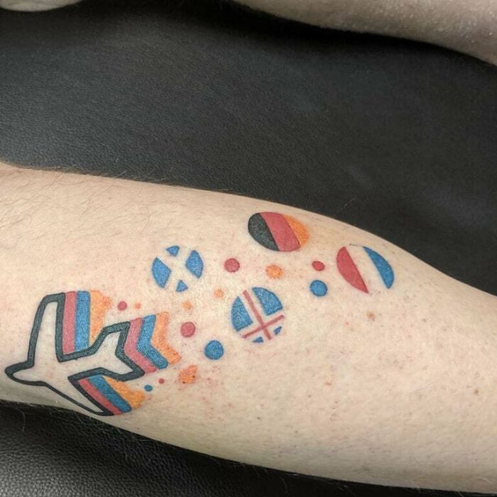 Lower leg tattoo with colorful airplane and flag designs.