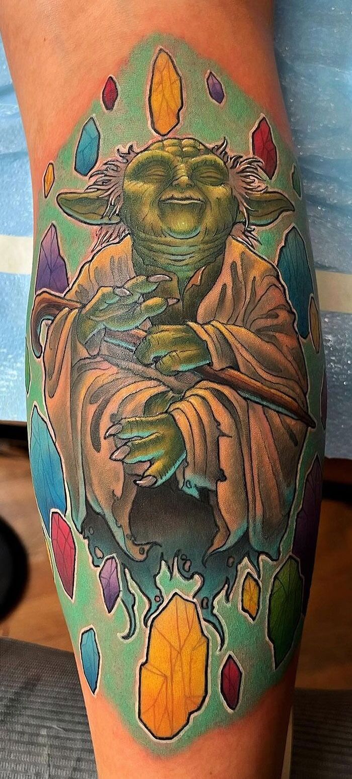 Lower leg tattoo of a character surrounded by colorful crystals.