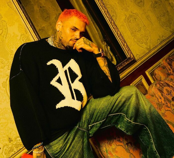 Celebrity in casual attire with red hair, sitting in a decorated room.