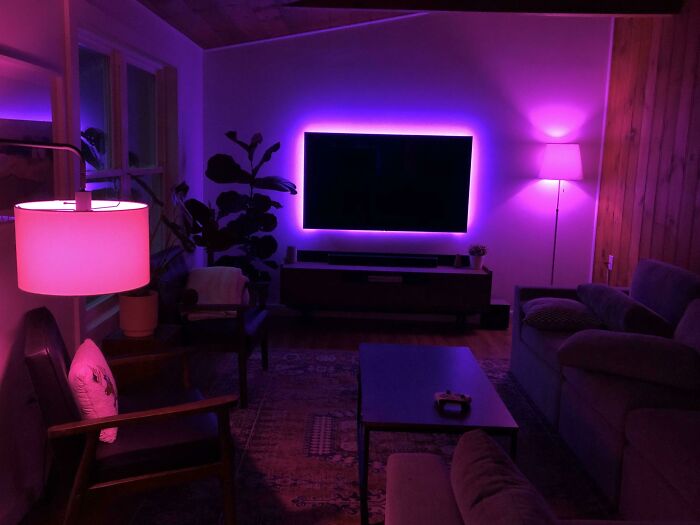 Living room with modern home decoration, featuring purple ambient lighting and comfortable seating arrangement.