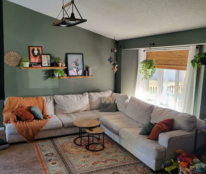 Cozy living room with creative decoration ideas, featuring a large beige sectional sofa, shelves with plants, and a patterned rug.