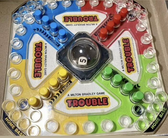 Vintage Trouble board game with colored pieces and pop-o-matic die roller, illustrating humor older generations recall.