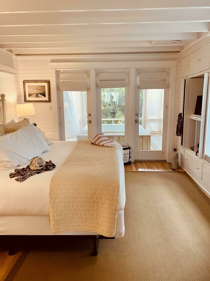 Cozy bedroom with white walls, large windows, and a plush bed, showcasing stylish home decoration.