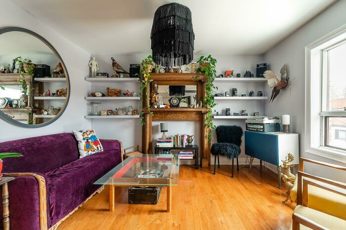 Home decoration idea featuring a vibrant living room with a purple sofa, glass coffee table, and modern wall shelves.