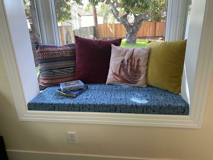 Cozy window seat decorated with colorful cushions and books for creative inspiration.