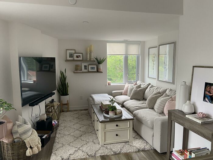 Home decoration ideas with a cozy living room, white sofa, soft pillows, and wooden shelves, creating a serene atmosphere.