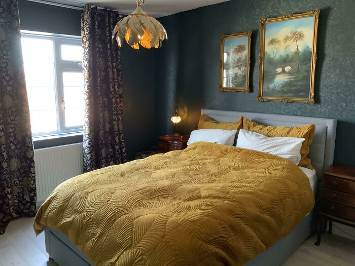 Cozy bedroom with green walls, gold bedding, creative lamp, and vintage art; perfect creative decoration inspiration.