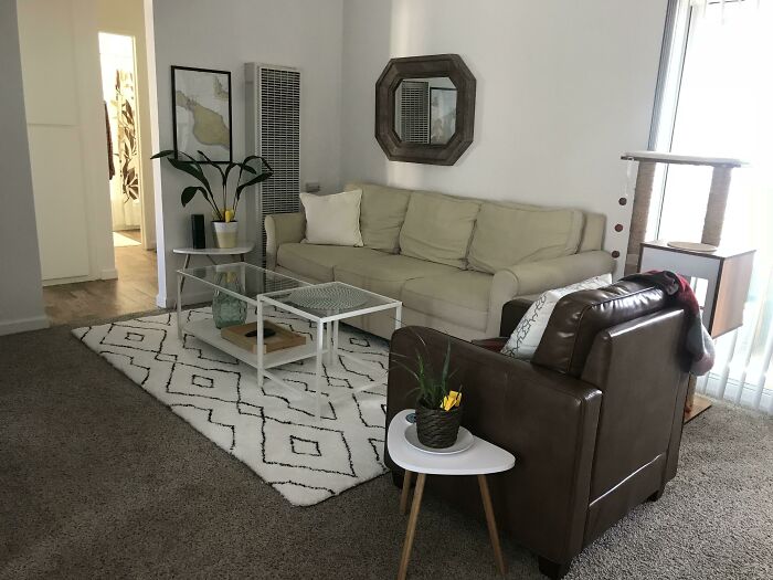 Cozy living room with modern home decoration, beige sofa, geometric patterned rug, and a glass coffee table.