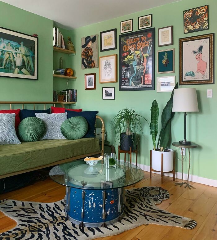 Cozy living room with eclectic decorations, green walls, plants, and art-filled gallery wall for creative inspiration.