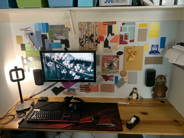 Creative inspiration desk setup with art-covered wall, computer, and decorative items.