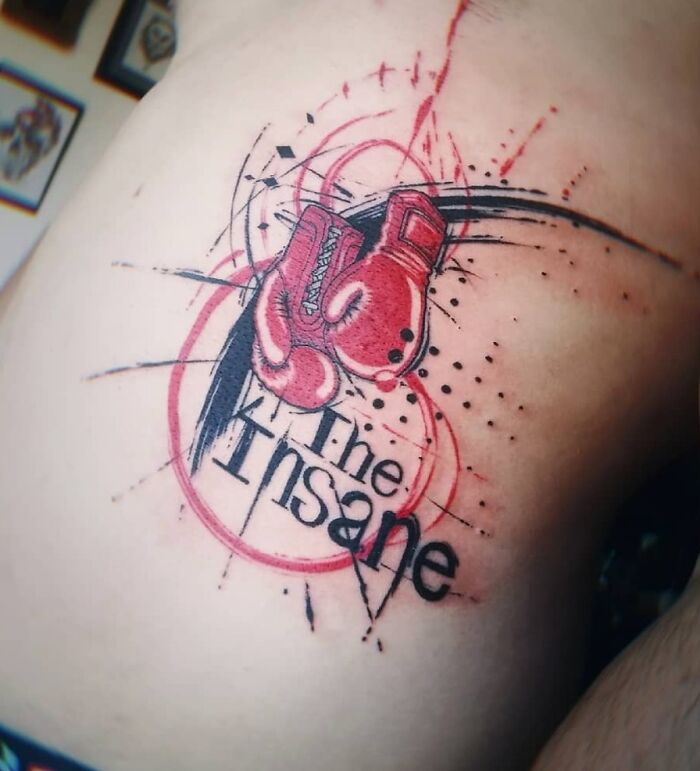 Red ink tattoo featuring boxing gloves and abstract design with the words "The Insane" on skin.