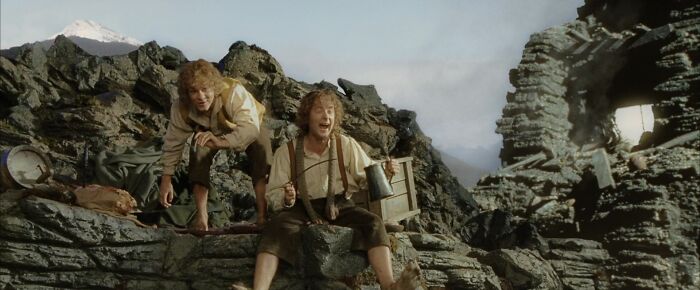 Two characters from a movie, representing iconic best friend duos, seated on rocky terrain with expressions of surprise.
