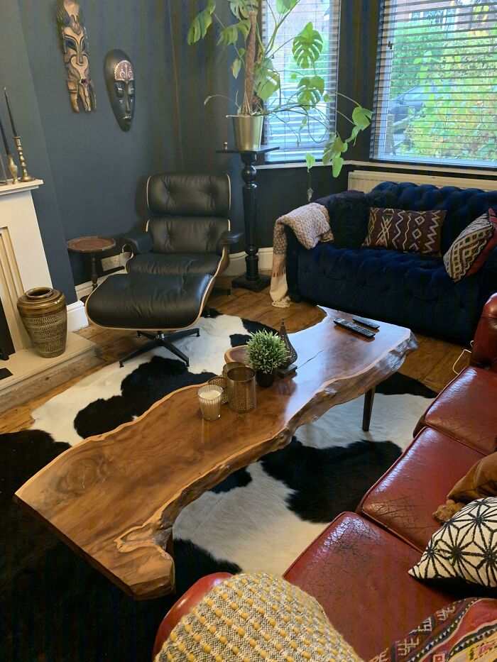 Cozy living room with stylish home decoration, featuring a wooden coffee table, leather chair, plants, and wall art.