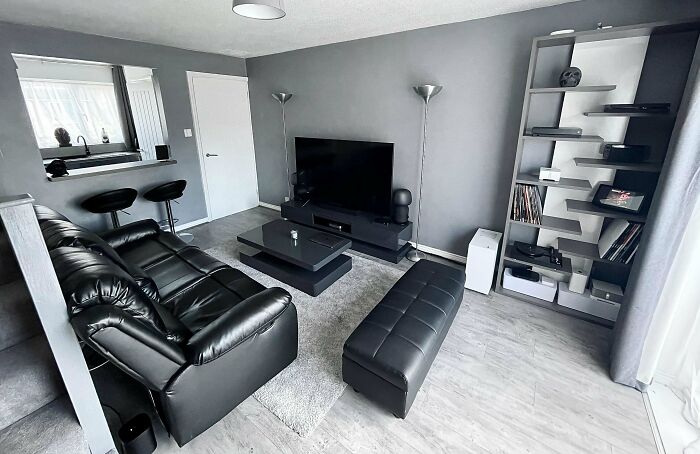 Modern living room with black leather furniture and a sleek entertainment setup, showcasing stylish home decoration ideas.