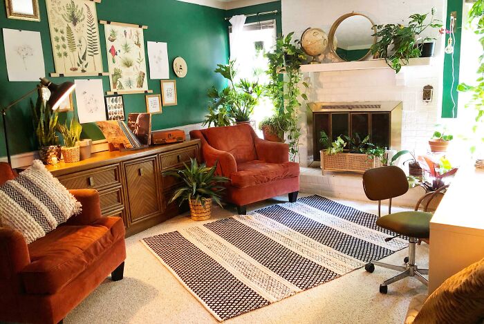 Creative inspiration in a cozy living room with green walls, plants, and orange chairs.