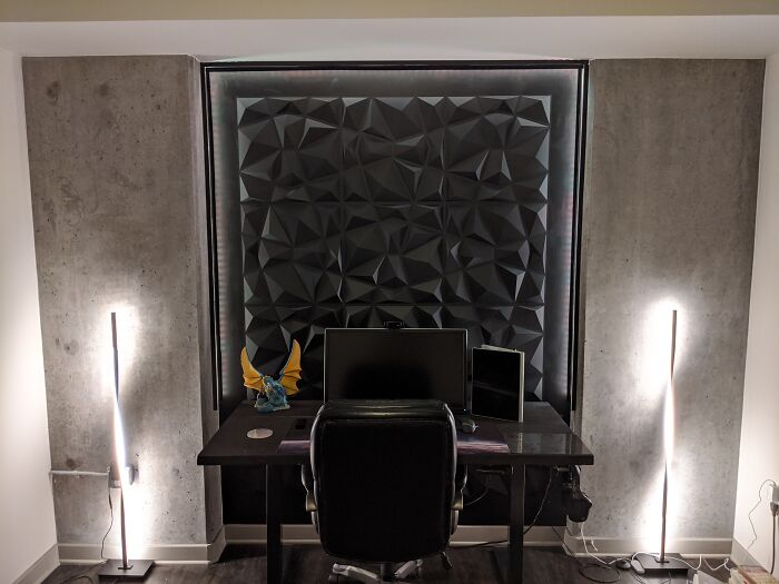 Modern home office decoration with geometric wall panel, desk, and ambient lighting for a stylish update.